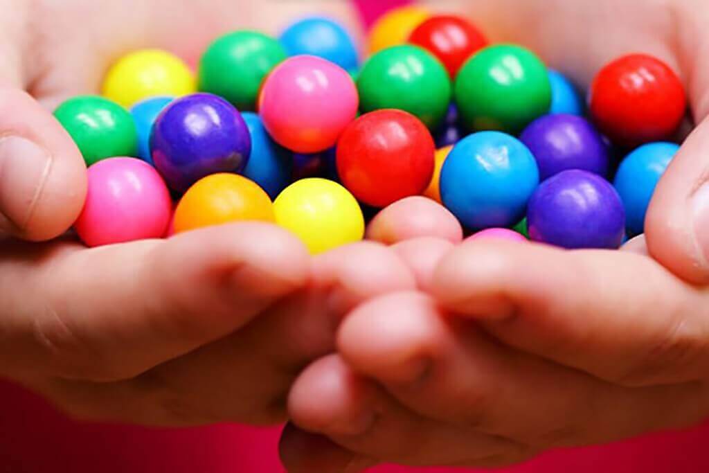 hand full of the same sweets but in different colours depicting importance of hotels to understand and constantly evaluate their compset