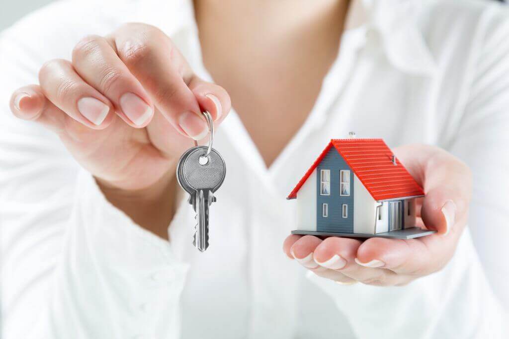 person holding keys and a model house reflecting vactaion rentals being added to search results in google travel