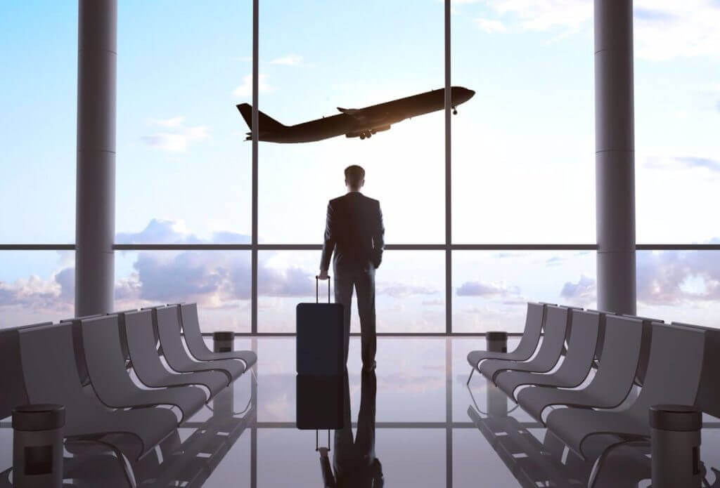 man in airport lounge looking at plane taking off preparing for his business travel