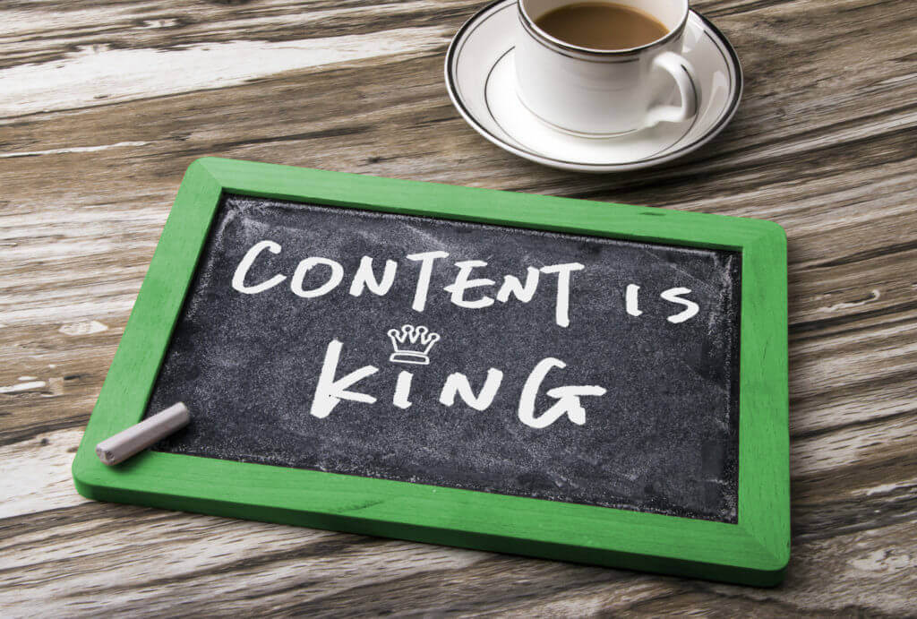 white chalk writing on a blackboard which says content is king