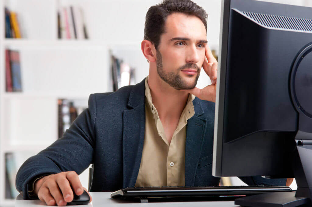 man staring at a computer screen possibly looking online at a hotel as they encourage direct bookings