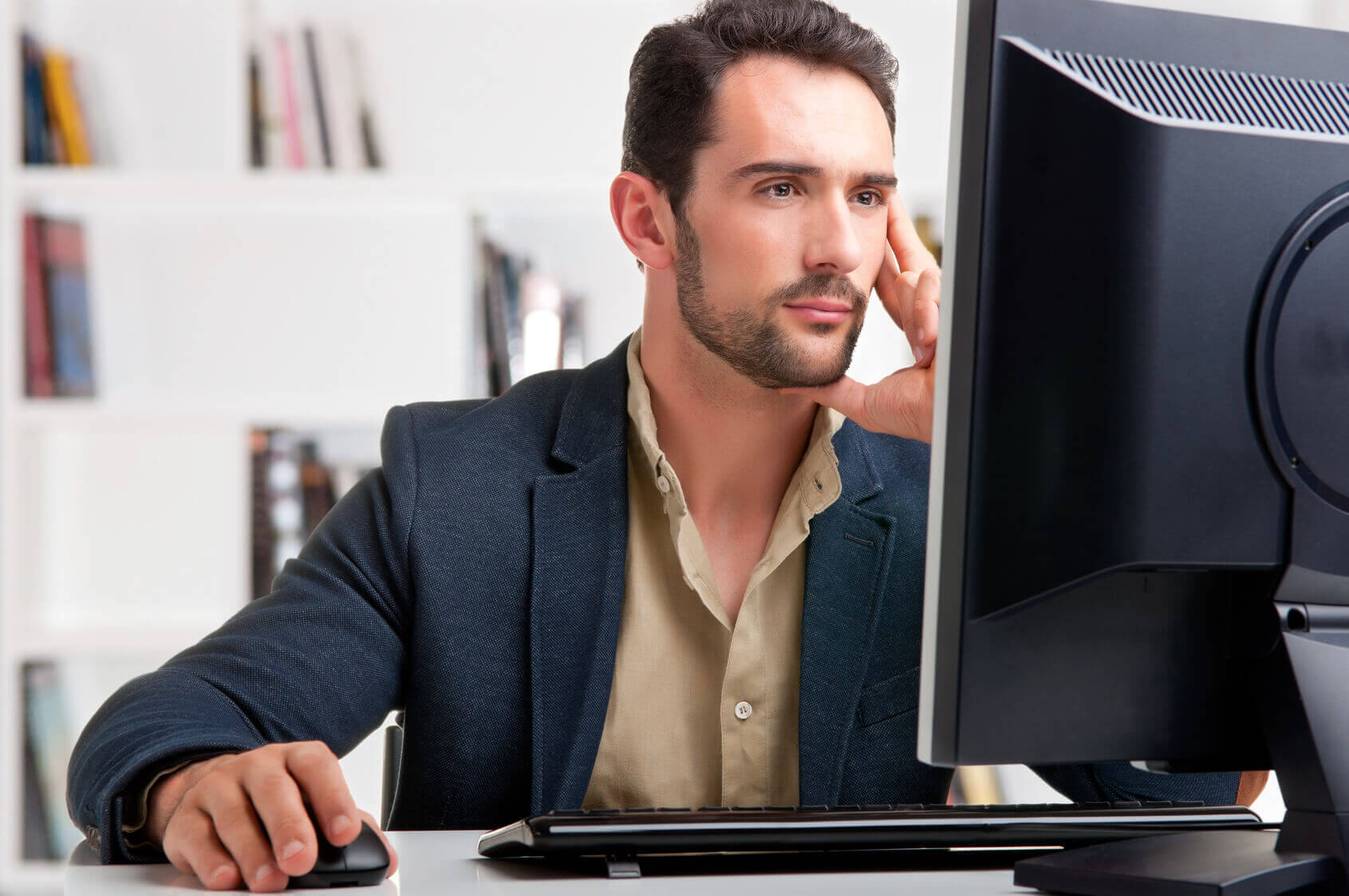 man staring at a computer screen possibly reading an email before booking a hotel