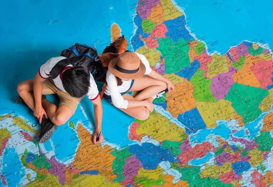 two people sitting on a map as they look again at engagement with travel