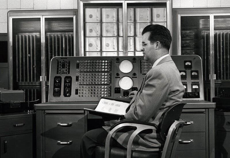 black and white picture of man sitting next to old technology depicting how a hotel is slow to invest in rms technology