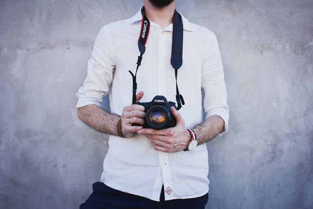 man holding camera taking photos illustrating importance of quality hotel photography