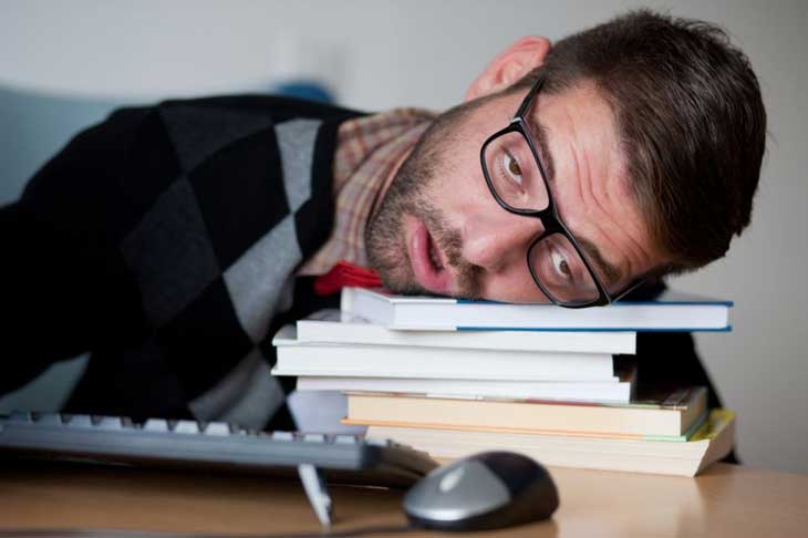 man laying his head on books looking weary from searching a website