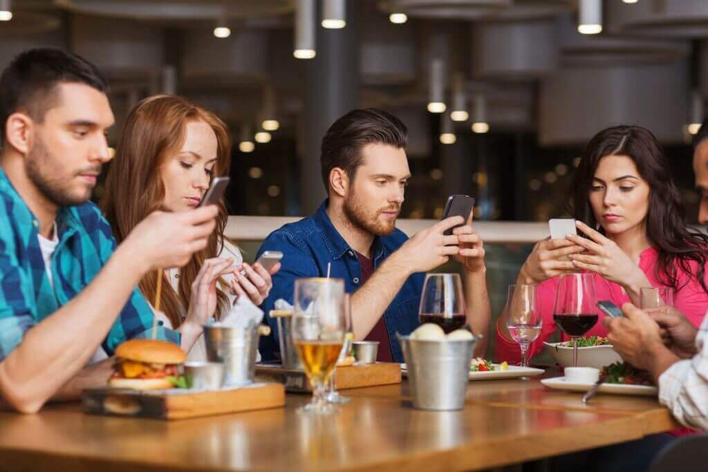 4 individuals in a restaurant on mobile phones provides opportunity for increased revenue