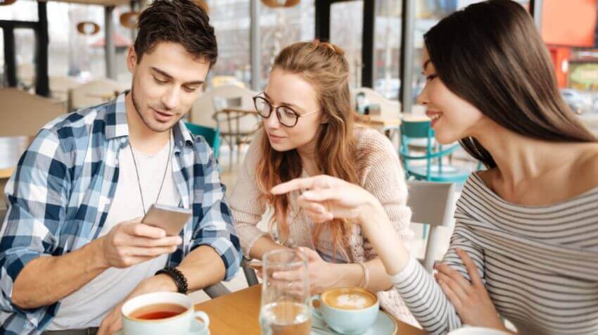 3 gen zers looking at mobile phone possibly reviewing travel plans