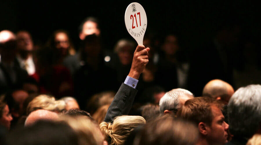 man holding up auction paddle