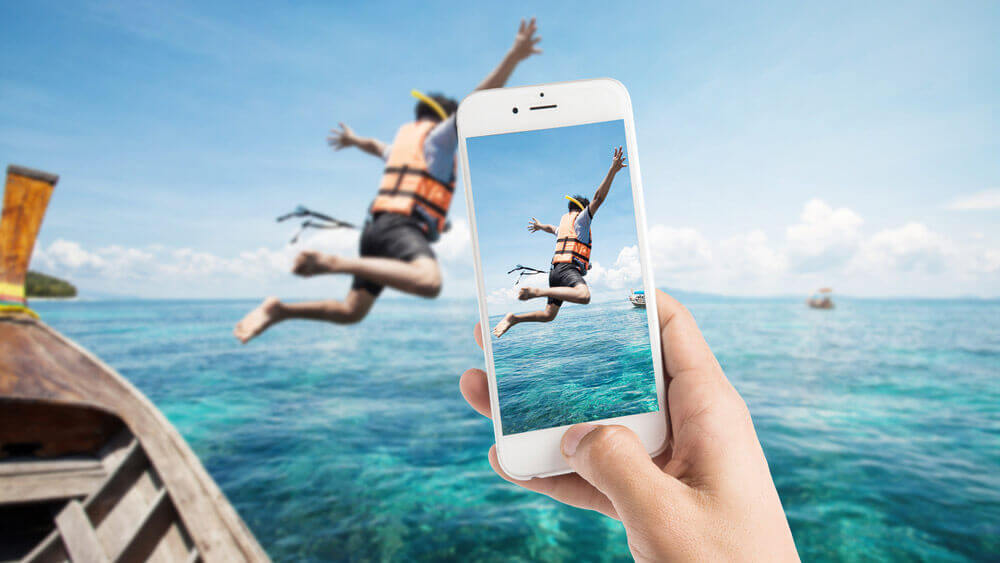 person being recorded on a mobile phone having a fun time jumping into the ocean reflecting the importance of a great hotel guest experience