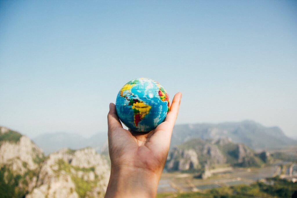 hand hiding a small globe considering whether to travel or not