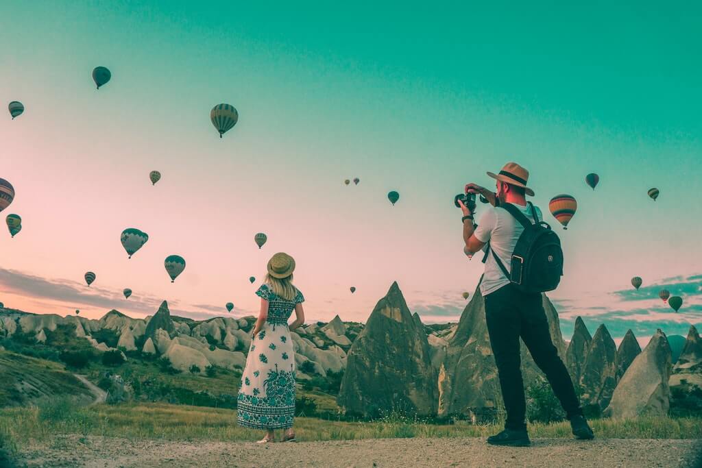 man taking picture of lady lookng at air balloons as part of an influencer marketing campaign