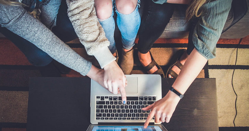 3 people looking at a laptop as they see hotel upsell opportunities presented via digital marketing