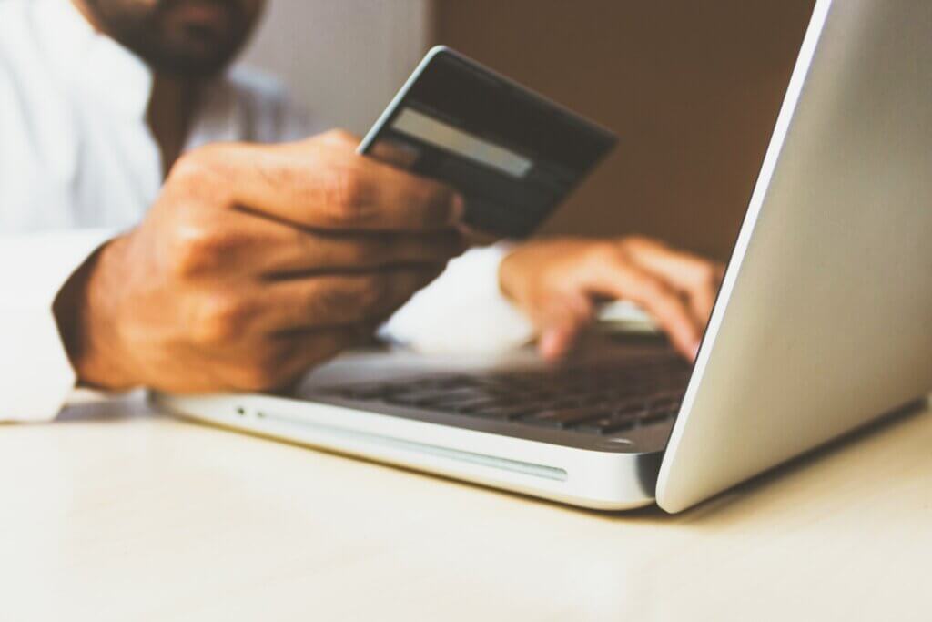 man on a laptop with a credit card possibly booking a hotel room reflecting the importance for hoteliers to consider flexible payment options