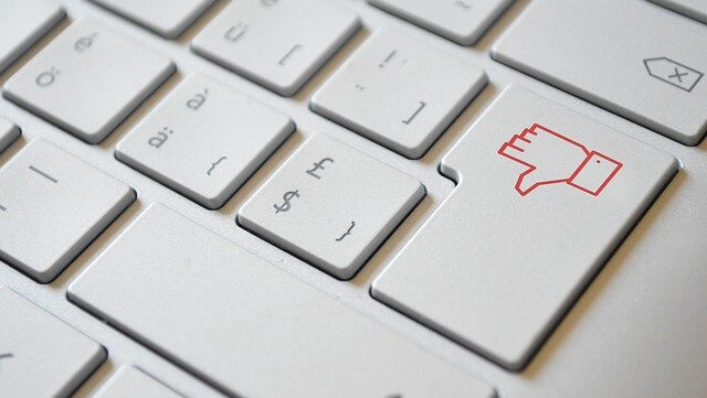 keyboard with a red thumb pointing down reflecting impact on a hotel of a negative review