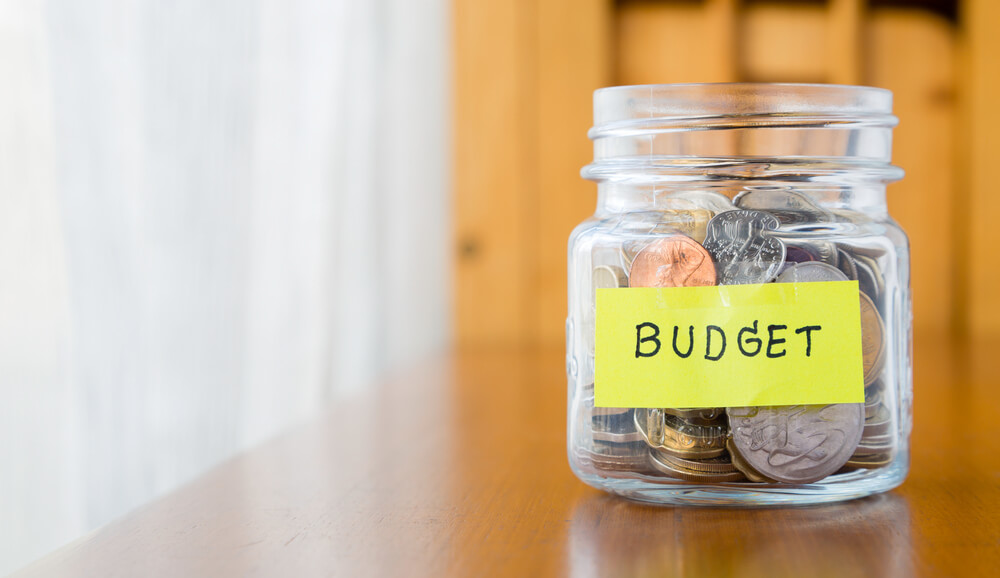 glass jar with money inside and the word budget written on a label on the front