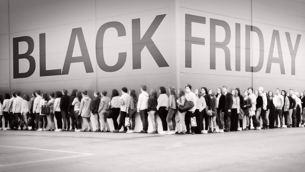 queue of people with the words black friday written above them on the side of a shop wall