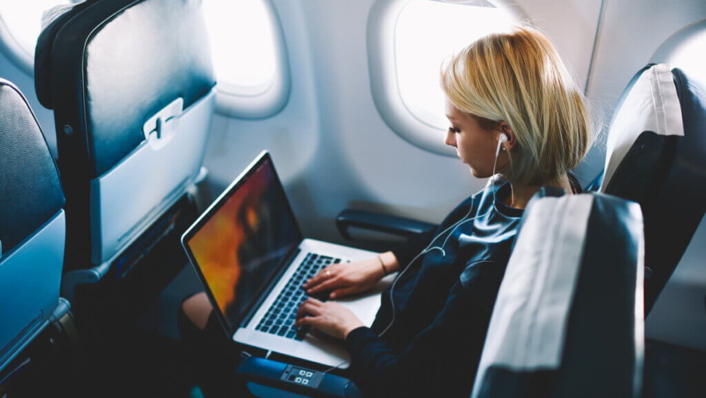 lady on plane with laptop reflecting increase in business travel but not yet fully recovered post pandemic