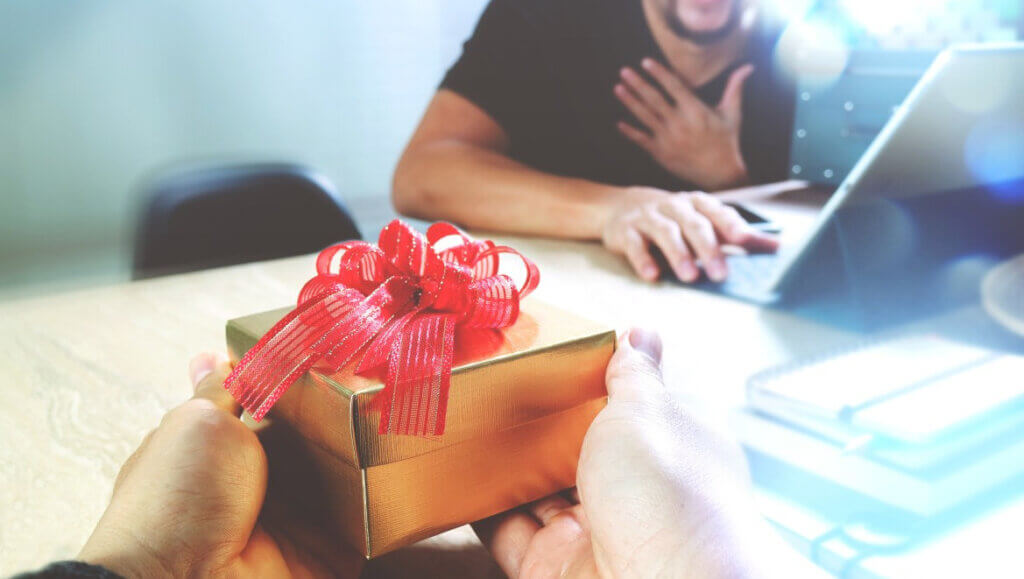 box with a ribbon being handed to a person on a laptop reflecting impact of dynamic packaging solutions on travelers booking their trip