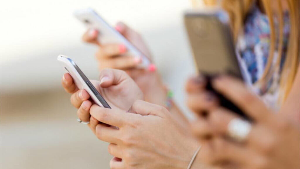 people looking at mobile phones illustrating how hotels can connect with travelers via advertising of cyber deals for black friday cyber monday and travel tuesday