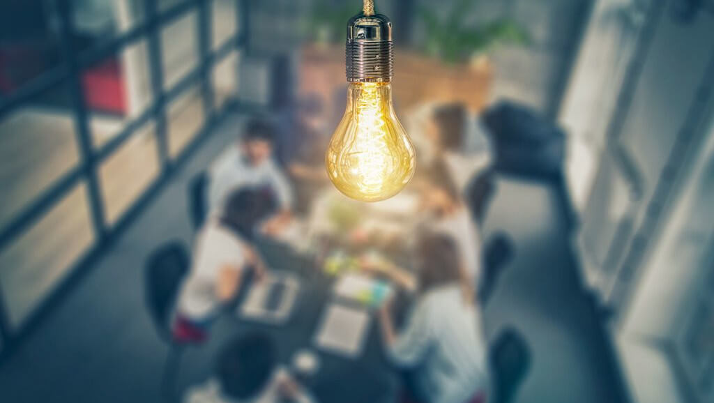 bright light bulb with a meeting of sales marketing and revenue professionals coming together to develop a unified commercial strategy