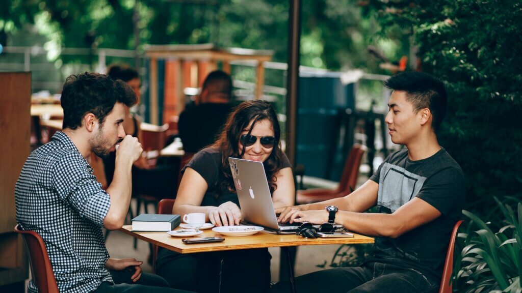 three people looking at a laptop possibly browsing social media content