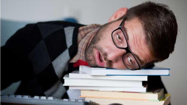 person looking tired and laying their head on a pile of books reflecting the big things that keep hotel sales managers up at night
