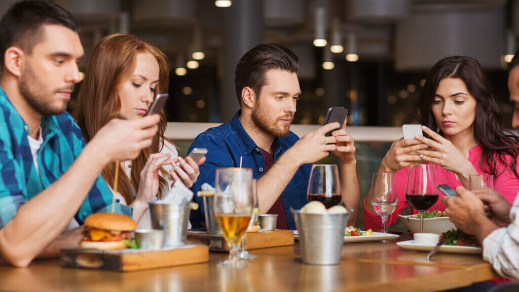 4 people on their mobile phone possibly at a hotel bar reflecting the importance of first party data