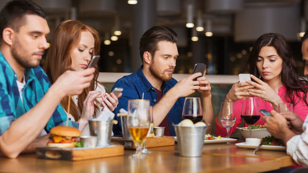 4 people on their mobile phone possibly playing games illustrating the impact of gamification in loyalty programs to engage members with rewards