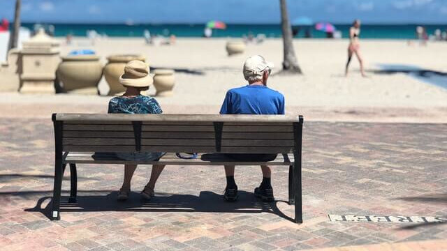 american travelers sitting on a bench by the beach
