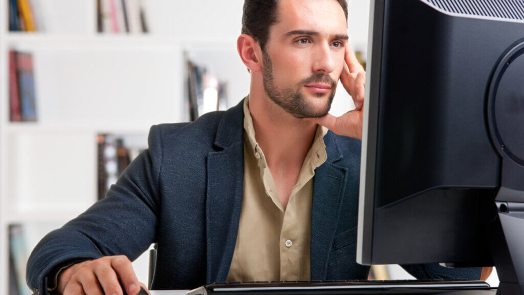 man looking at a website on a computer monitor maybe a hotel metasearch site comparing prices