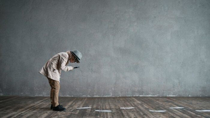 person with a magnifying glass following footprints reflecting the revenue management trends coming up when looking at real world hotel examples