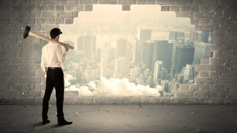 person breaking down a wall reflecting how hotels are breaking down barriers and reclaiming power in website management