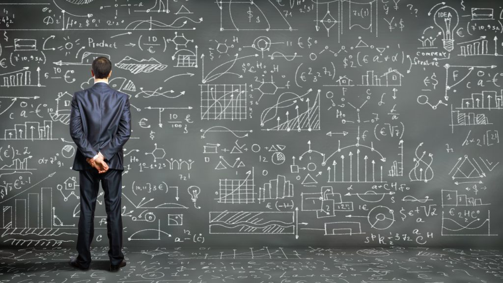 man standing in front of calculations and algorithms reflecting the multiple different aspects a hotel must consider when budgeting for 2024