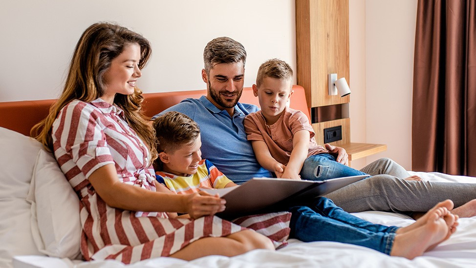 family sitting on a hotel bed illustrating the value of hotel package offerings to drive bookings, occupancy and revenue