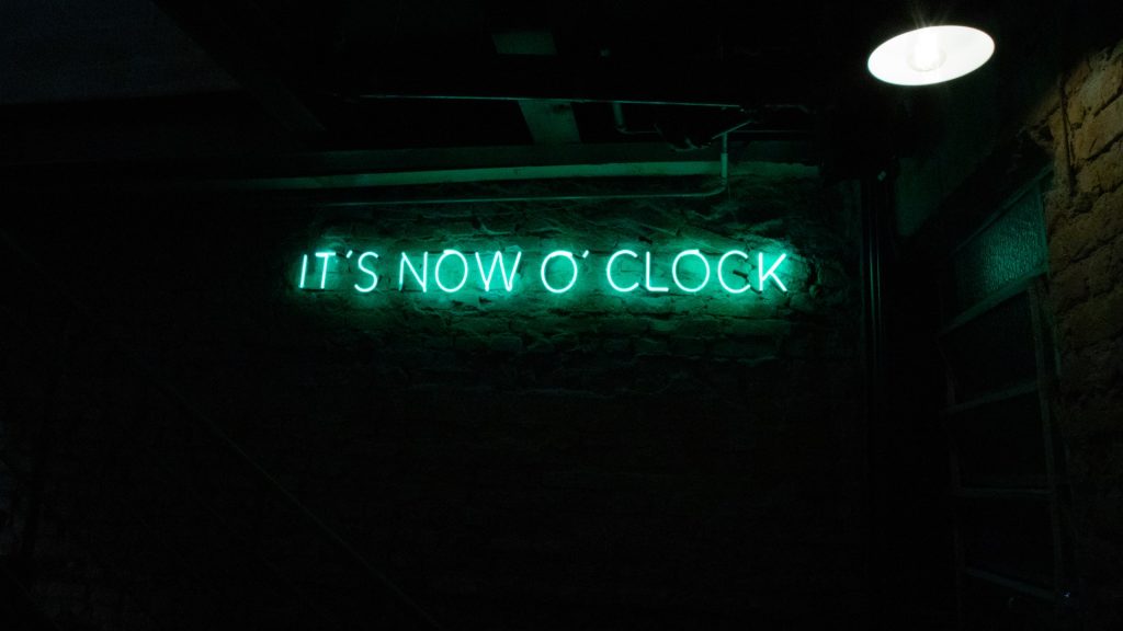 neon sign with a message saying time to act now much in the same way hotels can increase direct bookings with urgency tactic