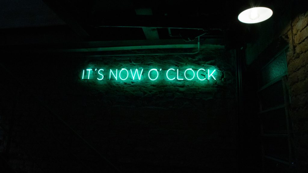 neon sign saying it is now o clock reflecting the importance of developing strategies to avoid needing last minute bookings