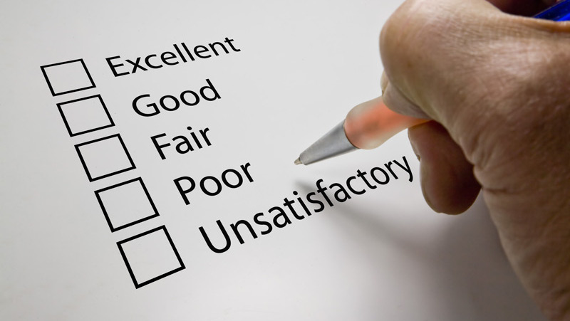 person holding a pen above a feedback tick box as they reflect on the price of a recent hotel stay illustrating the impact of guest reviews based on rates