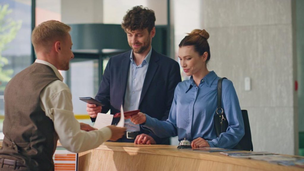 2 guests at a hotel front desk illustrating the importance of mapping the modern guest journey and the key touchpoints to optimise and drive greater guest satisfatcion