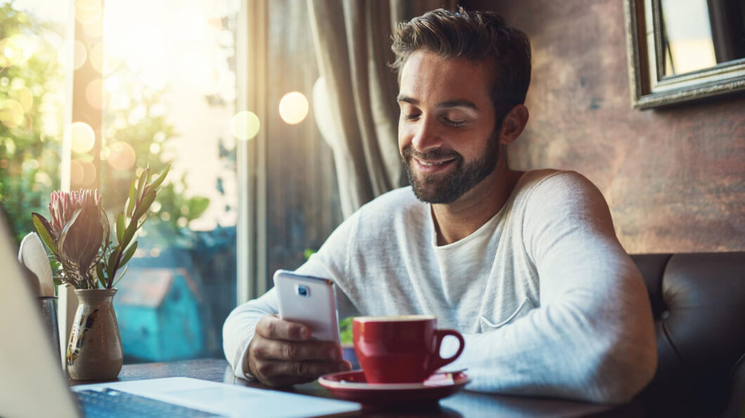 smiling person looking at their mobile possible receiving a pre-arrival message for a hotel