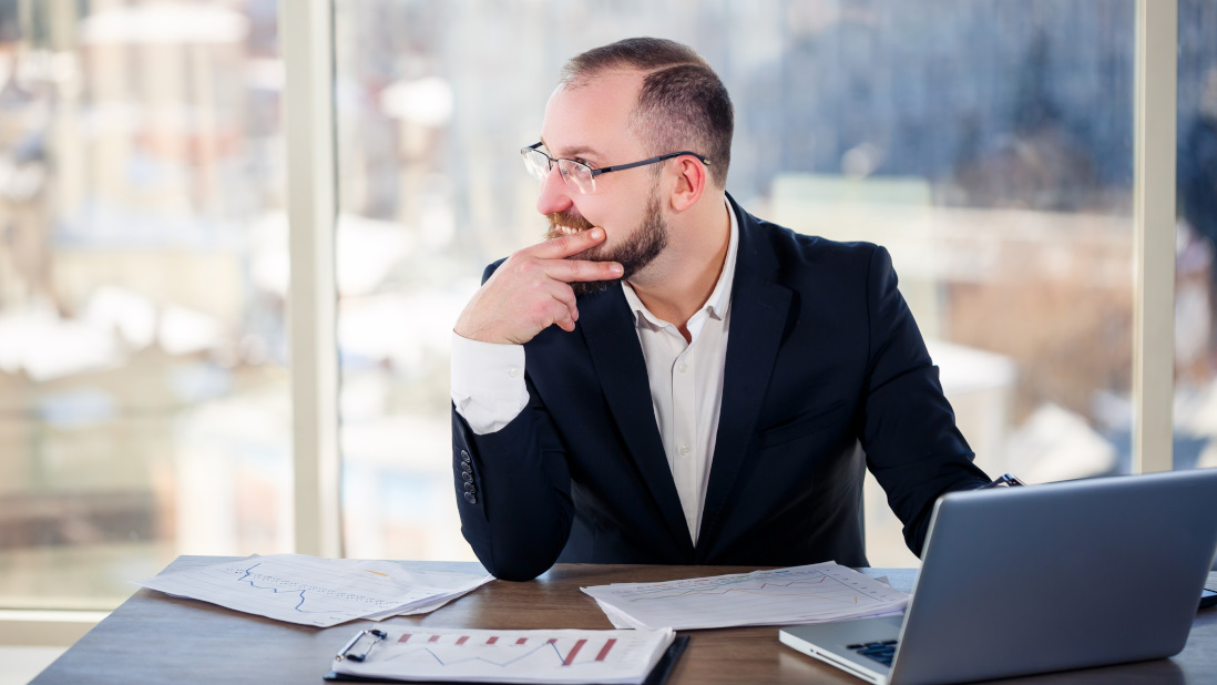 man at a desk possibly a hotelier contemplating their hotel tech stack and whether to replace or integrate tools